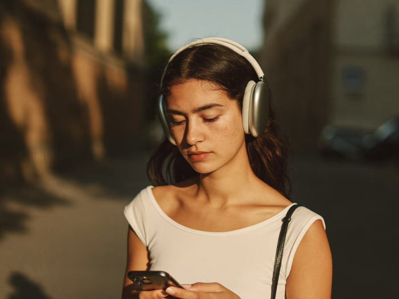 Una ragazza cammina per strada ascoltando qualcosa in cuffia